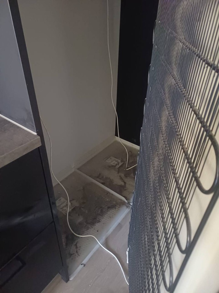 Dusty area under refrigerator before cleaning